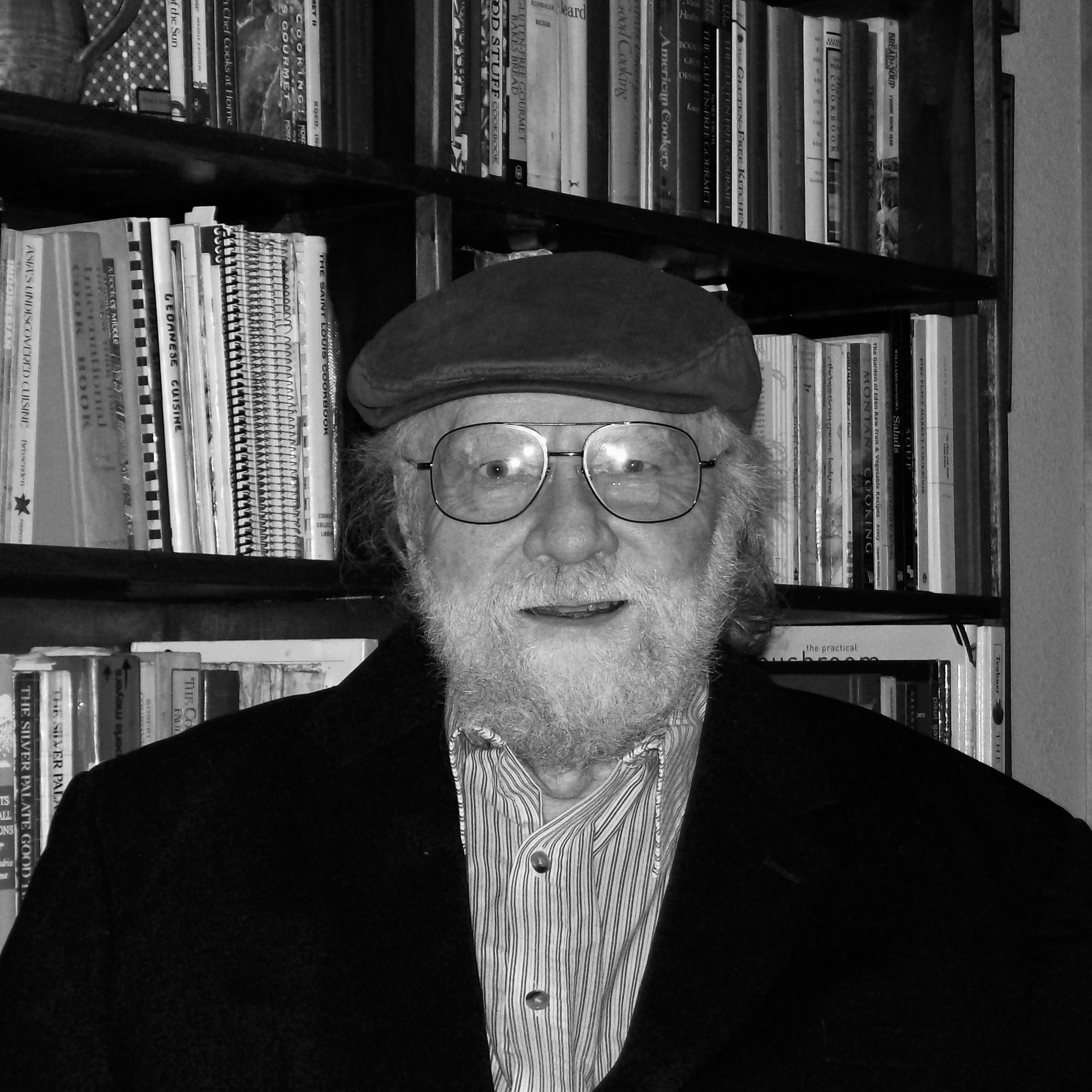 Photograph of Don Doig standing beside a bookshelf