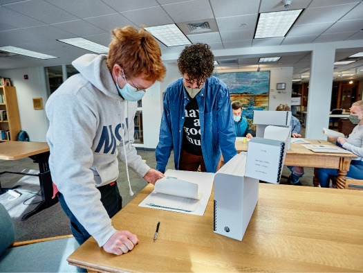 Image of students looking through some of the collections availble at MSU in the library's reading room.