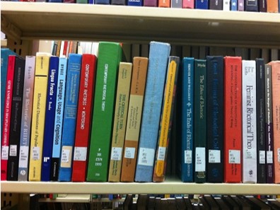 Image of library books stacked on metal shelf.
