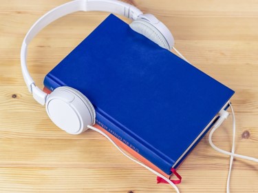 Image of blue print book with white headphones over it.